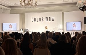 Color_Wow_Gründerin_on_Stage - Friseur Bonn ❤️ Laurentius Excellence in Hair ⭐ Audience seated in a conference hall watching a COLOR WOW product presentation on a bright stage with two screens showing the speaker.